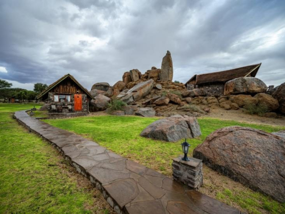 Scenic view of lodges by large rocks and grassy paths.