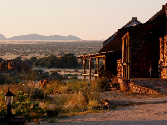 A tranquil scene of a stone house at dusk near mountains.