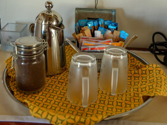 A tray with a coffee pot, sweeteners, and mugs.