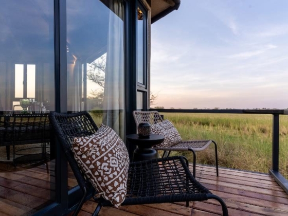Relaxing balcony with chairs overlooking a grassy landscape.