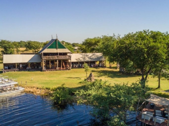 Scenic view of a lodge by the water with lush greenery.